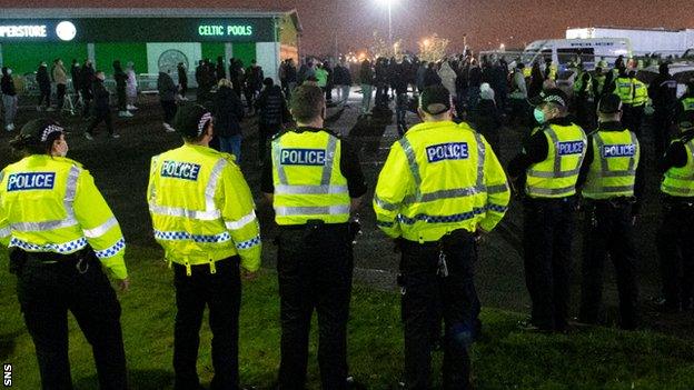 Police keep an eye on supporters gathered outside Celtic Park after the 2-0 loss to Ross County