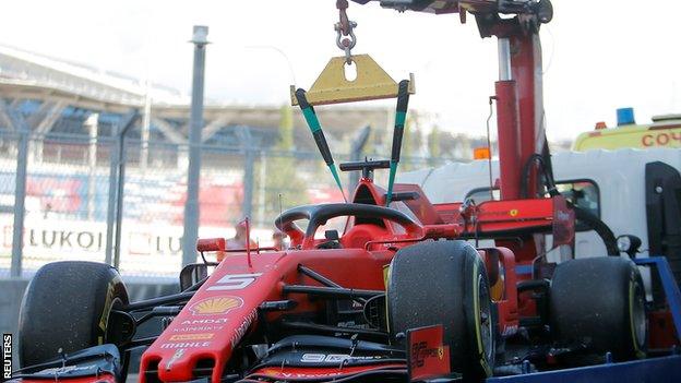 Sebastian Vettel's Ferrari is towed back into the pits