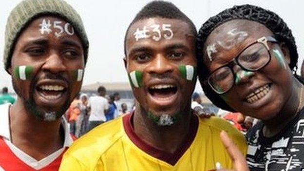 People with their faces painted with the national green and white colours, and different naira denominations on their forehead, pose during a Lagos demonstration