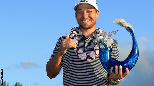 Xander Schauffele poses with the tournament trophy