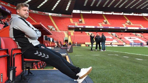 Charlton Athletic manager Karl Robinson sits in the dugout at The Valley