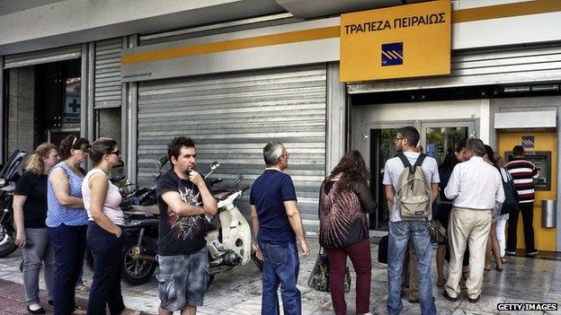 People waiting in line to withdraw money from an ATM in Greece