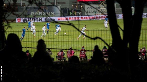 Icelandic football fans who missed out on tickets climb trees and watch between gaps in the fence