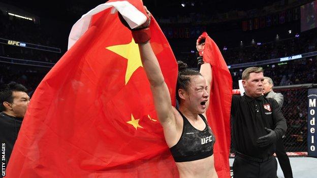 Zhang Weili holds up the Chinese flag in celebration after beating Joanna Jedrzejczyk at UFC 248