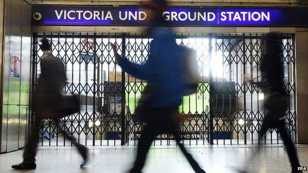 Commuters walk past a closed Victoria Tube Station on 9 July