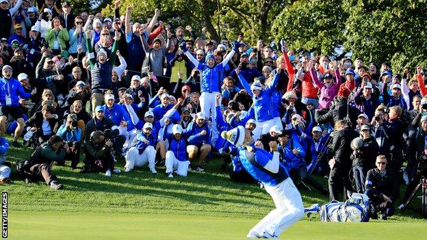 The Europe team rise to their feet along with supporters on the side of the 18th green after Pettersen sinks the winning putt