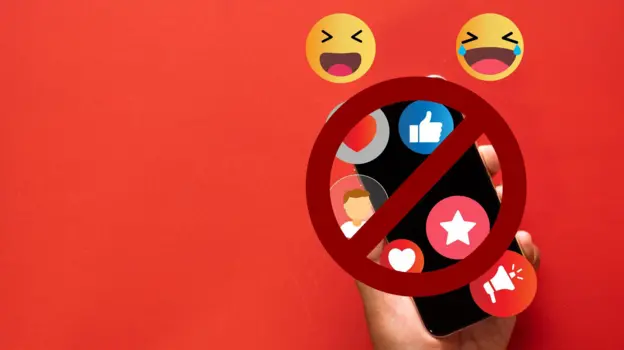 Emojis float over a smartphone, held by a hand against a red background. A stop sign is slapped over the top of the image.