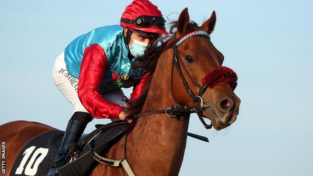 A jockey wearing a face mask while riding