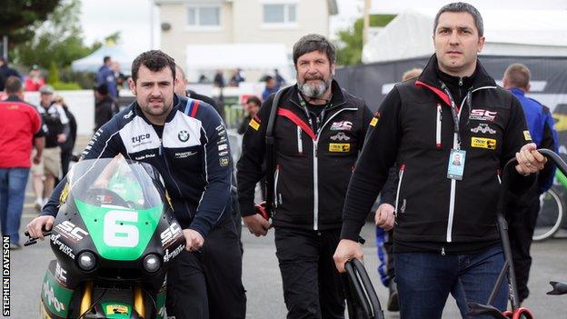 Michael Dunlop wheels his Supertwins bike back to his garage after Wednesday evening's race postponement