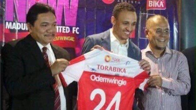 Peter Odemwingie holds up his Madura United shirt