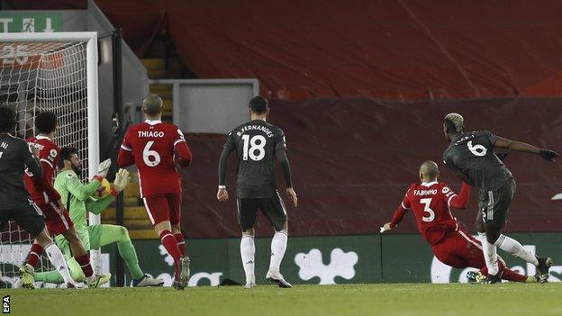 Alisson (second left) saves from Paul Pogba (right)