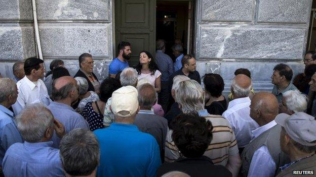 People, most of them pensioners, argue with a staff member outside a closed National Bank branch