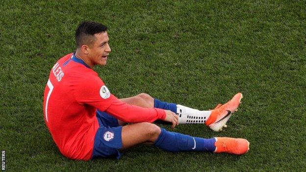 Alexis Sanchez sits on the ground after suffering an injury