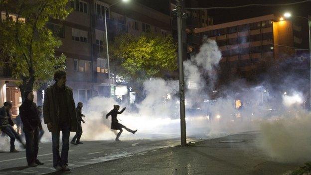 A protester kicks off a tear gas canister during clashes with Kosovo police in front of the central police station in Kosovo capital Pristina after the arrest of a prominent opposition politician Albin Kurti on Monday, Oct. 12, 2015.