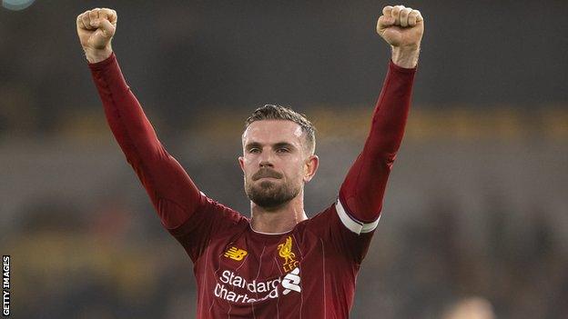 Jordan Henderson holding his hands above his head, saluting the Liverpool fans