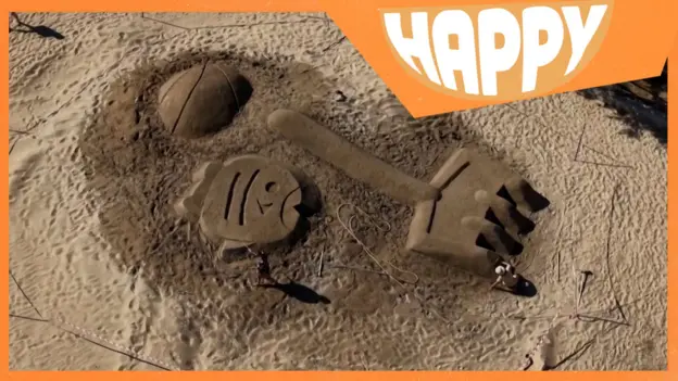 Giant sand sculptures and the Happy logo