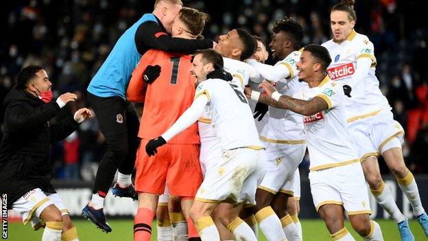 Nice players surround their goalkeeper after beating PSG on penalties