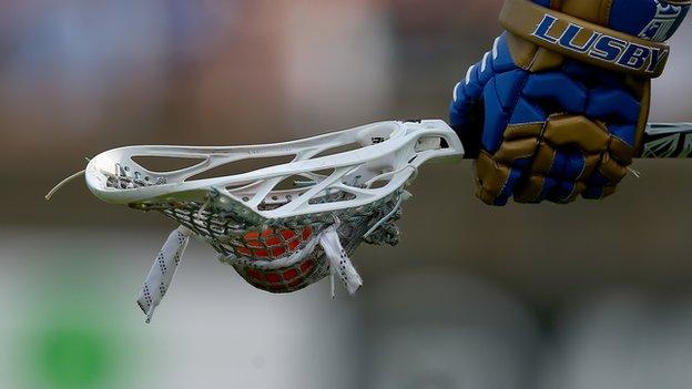 hand carrying a lacrosse racket and ball