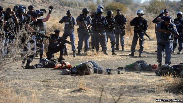 Police surrounding fallen miners after they opened fire during clashes near a platinum mine in Marikana.