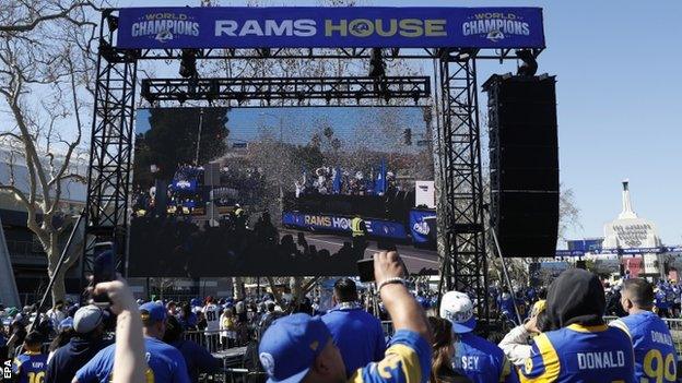 Fans watch the Los Angeles Rams' trophy parade on a giant screen at the Los Angeles Coliseum