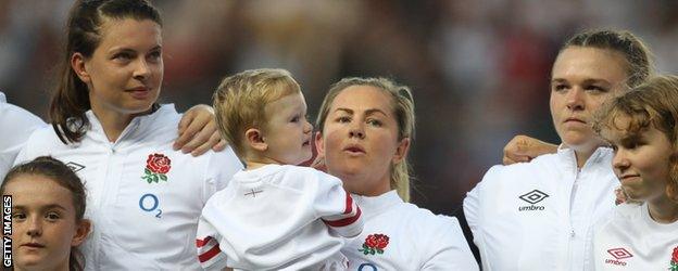 Marlie Packer holds Oliver while singing the anthem