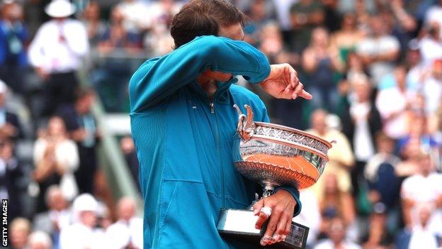 Rafael Nadal wipes his eyes while holding his trophy