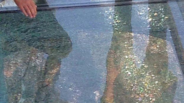 This photo taken on October 5, 2015 shows people standing by a cracked glass tile on a glass-bottomed walkway in Yuntaishan in Jiaozuo, central China's Henan province.