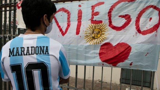 A fan wearing a Maradona Argentina shirt looks at a tribute in Buenos Aires