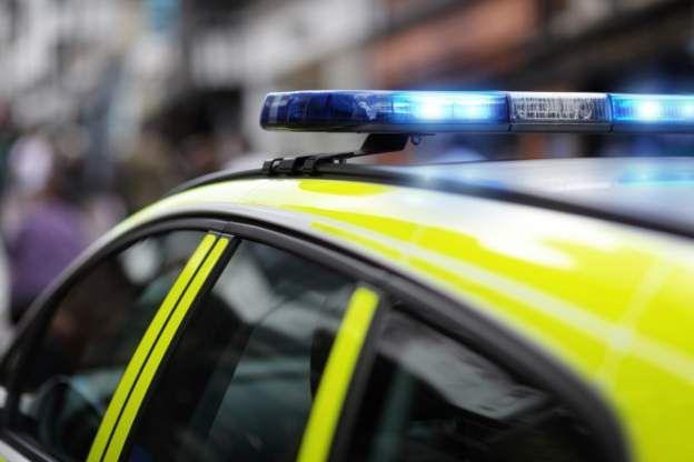 The top of a police car, with blue lights flashing. The background is blurred