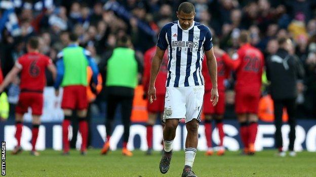 A dejected Salomon Rondon of West Brom walks away while Huddersfield's players celebrate at The Hawthorns