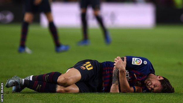 Lionel Messi on the floor in pain holding his right arm