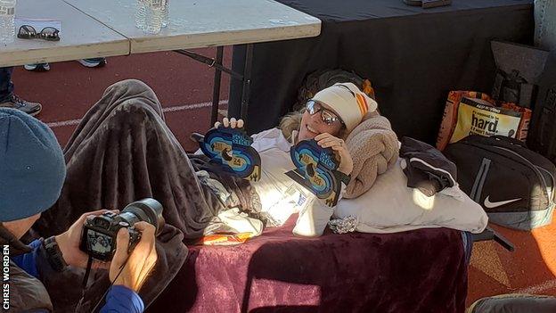 Camille Herron lies down while posing with her Desert Solstice trophies