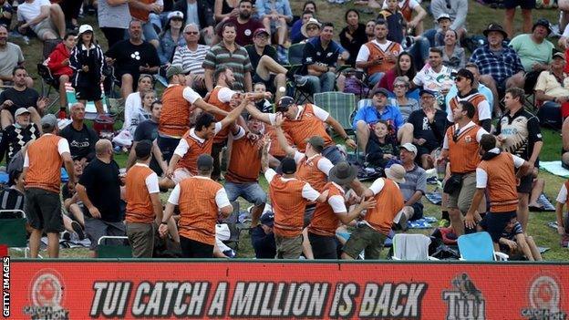 Cricket fans attempt to catch a six in the crowd