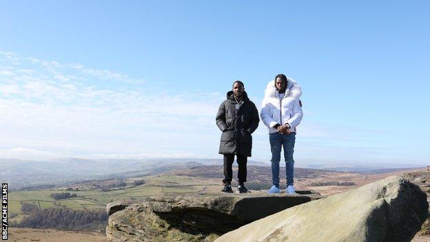 Krept and Konan stand on top of a hill.