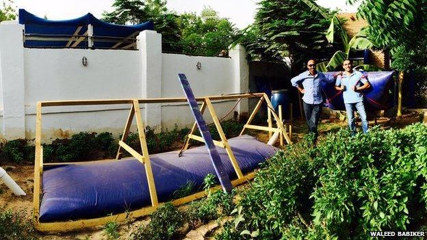 Khartoum franchise owner Waleed Babiker (left) stands next to his digester in Khartoum