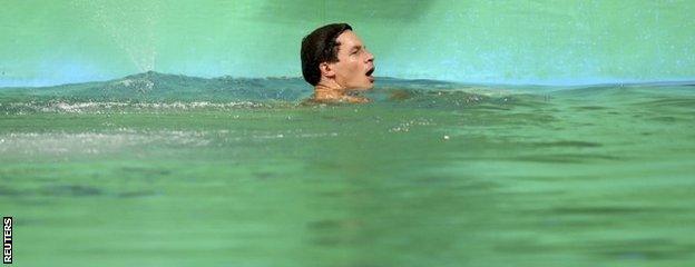 Patrick Hausding of Germany swims in the green coloured water of the diving pool