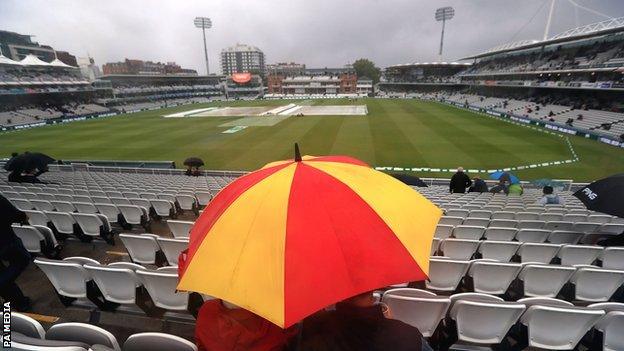 Spectator under an umbrella at Lord's