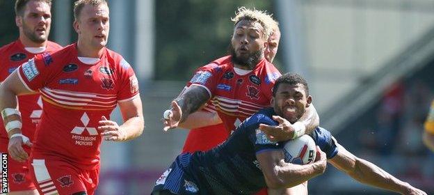 Kallum Watkins of Leeds takes a heavy challenge from Salford's Junior S’au