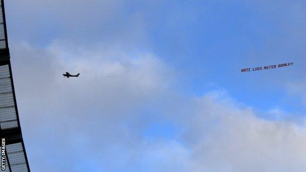 A banner reading 'White Lives Matter Burnley' is flown above Etihad Stadium before a Premier League match between Manchester City and Burnley