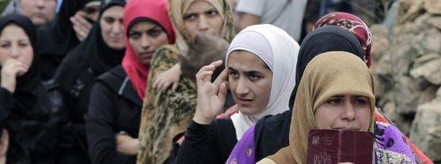 Syrian women wait in line to receive aid from an Islamic relief agency at a refugee camp in the town of Ketermaya, north of the port city of Sidon, Lebanon.