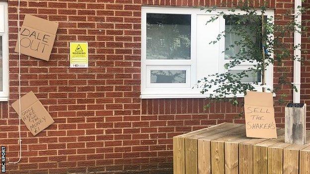 Signs saying 'Dale out' and 'sell the Shakers' were left at Gigg Lane