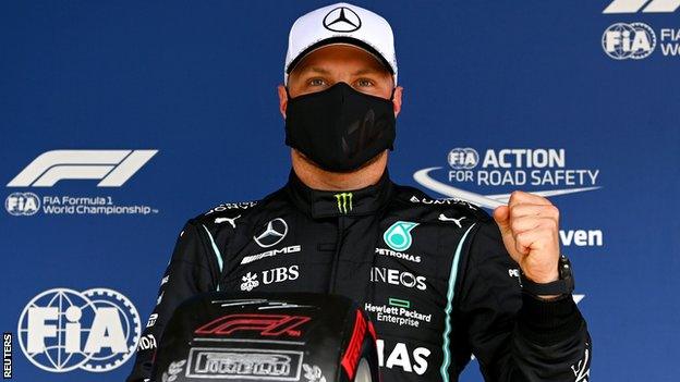 Valtteri Bottas holds up his pole position tyre