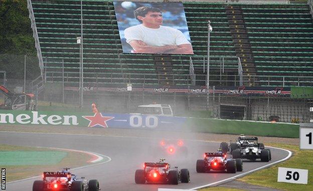 Drivers drive past a tribute to Ayrton Senna in the stands