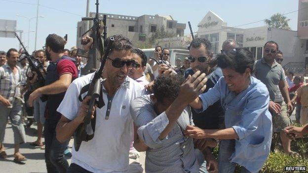 Police officers control the crowd (rear) while surrounding a man (front C) suspected to be involved in opening fire on a beachside hotel in Sousse, Tunisia, as a woman reacts 26 June 2015