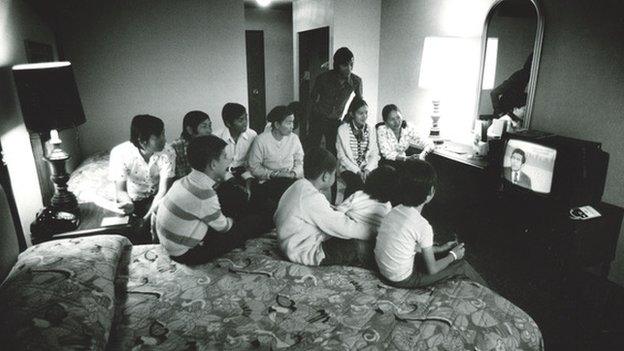 Germaine’s family in the hotel room watching news of the fall of Saigon