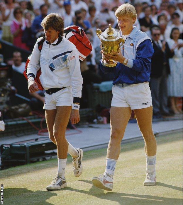 Boris Becker of Germany looks at the names engraved on the trophy as he walks off court with Kevin Curren after defeating him in the Men's Singles final of the Wimbledon Lawn Tennis Championship on 7 July 1985 at the All England Lawn Tennis and Croquet Club in Wimbledon in London, England.