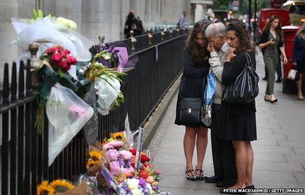 A family grieve as they stand next to a memorial