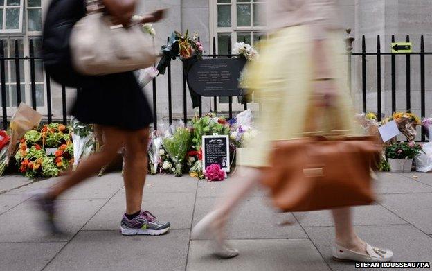 People walk past flowers in Tavistock Square