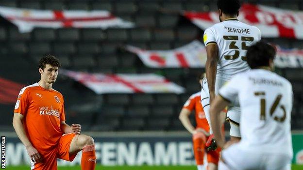 Cameron Jerome stands while fellow players take a knee