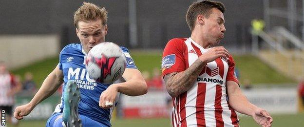 St Pat's Simon Madden attempts to clear under pressure from Ben Fisk of Derry